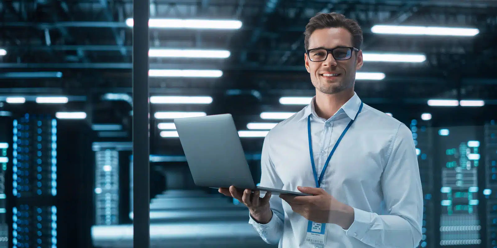 Man holding a laptop and standing in a workplace